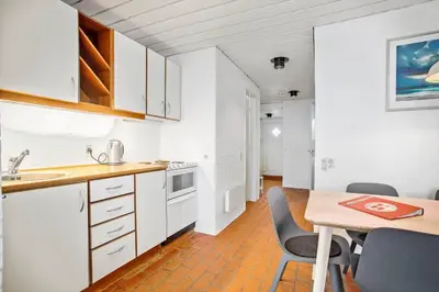 a kitchen with white cabinets and a table with chairs at JB181-Brovst-Strandvejen-150-Lejl-142 in Brovst