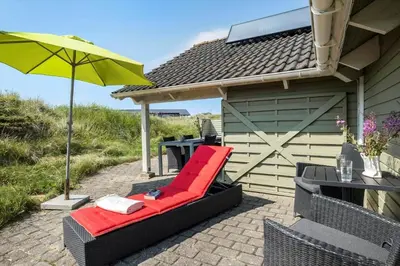 a patio with a red chair and a table and an umbrella at JB765-Brovst-Sletten-20 in Brovst