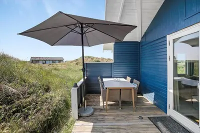 a table with an umbrella sitting on a deck at JB183-Frostrup-Svenstibakkevej-70 in Frøstrup