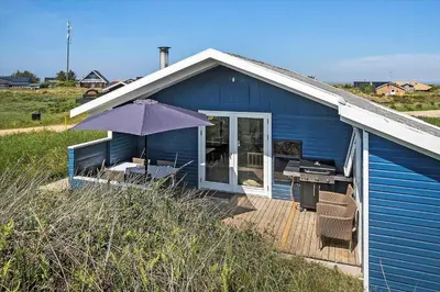 a blue house with an umbrella on a deck at JB183-Frostrup-Svenstibakkevej-70 in Frøstrup