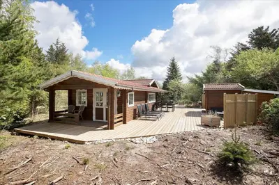 a small cabin with a deck in the woods at JB160-Fjerritslev-Skovstien-7 in Fjerritslev