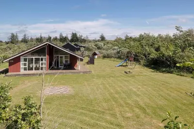 a small red house with a yard with a playground at JB326-Brovst-Kronvildtvej-134 in Brovst