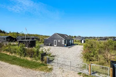 a house on a gravel road with a fence at JB307-Brovst-Kronvildtvej-130 in Brovst