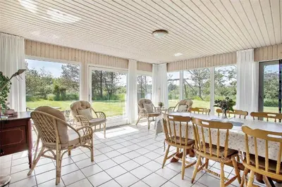 a dining room with a table and chairs and windows at JB785-Fjerritslev-Tolderstien-24 in Fjerritslev