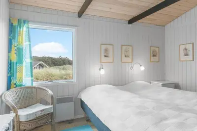 a bedroom with a bed and a window and a chair at JB306-Brovst-Redningsvejen-18 in Brovst