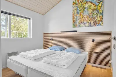 a bedroom with a large white bed with a painting on the wall at JB299-Brovst-Kronvildtvej-224 in Brovst