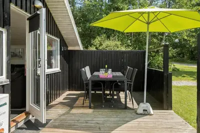 a dining table with a yellow umbrella on a deck at JB236-Fjerritslev-Ahornvej-22 in Fjerritslev