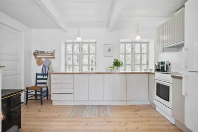 a kitchen with white cabinets and a wooden floor at JB199-Fjerritslev-Svinklovvej-403 in Fjerritslev