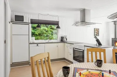 a kitchen with white cabinets and a table with chairs at JB128-Fjerritslev-Pilevej-2 in Fjerritslev