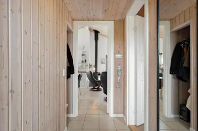 a hallway with wooden walls and a person sitting in a chair at JB234-Frostrup-Strandvejen-83-A in Frøstrup
