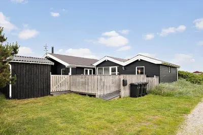 a black house with a fence and a yard at JB234-Frostrup-Strandvejen-83-A in Frøstrup