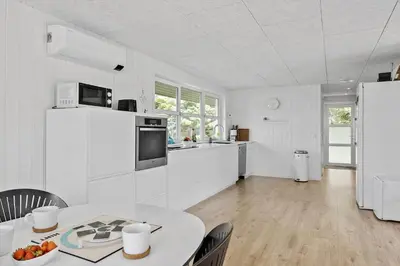 a white kitchen with a table and a refrigerator at JB318-Fjerritslev-Fiskerstien-10 in Fjerritslev