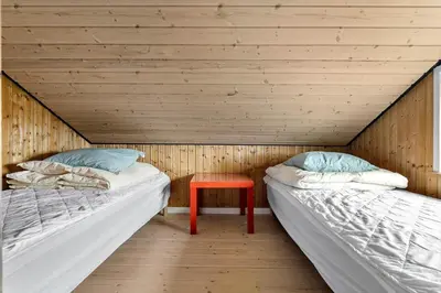 two beds in a wooden room with a red stool at JB187-Brovst-Kronvildtvej-128 in Brovst