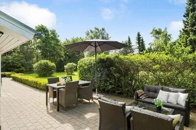 a patio with a table and an umbrella at JB716-Fjerritslev-Tyttebaerstien-16 in Fjerritslev