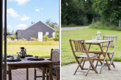 a wooden table and chairs sitting next to a field at JB239-Brovst-Kronvildtvej-208 in Brovst