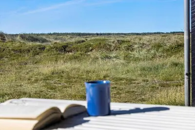 a blue cup sitting on a table next to a book at JB144-Frostrup-Horsbakkevej-7 in Frøstrup