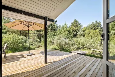 a wooden deck with an umbrella and a bench at JB696-Fjerritslev-Blabaerstien-56 in Fjerritslev