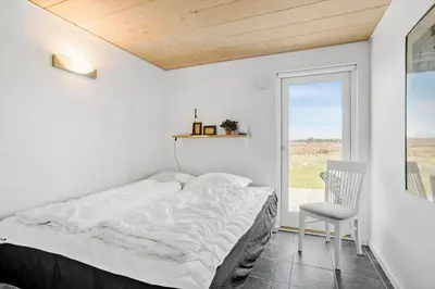 a bedroom with a bed and a chair and a window at JB203-Brovst-Kronvildtvej-35 in Brovst