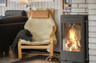 a person sitting in a chair in front of a fireplace at JB233-Brovst-Ejstrup-Strandvej-24 in Brovst