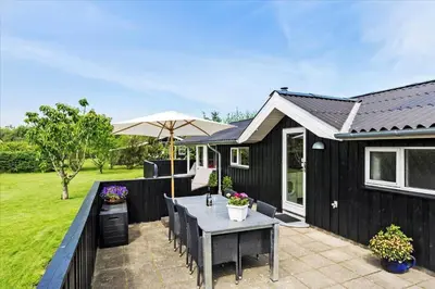 a black house with a table and an umbrella at JB166-Fjerritslev-Egevej-26 in Fjerritslev