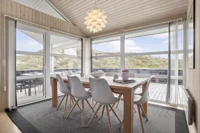 a dining room with a table and chairs and windows at JB705-Frostrup-Svenstibakkevej-82 in Frøstrup