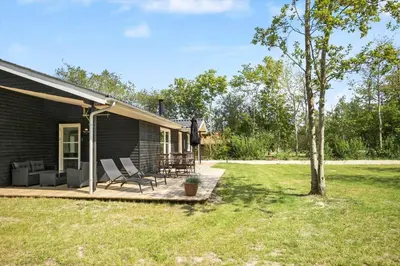 a house with a deck with chairs and a tree at JB324-Fjerritslev-Tyttebaerstien-42 in Fjerritslev
