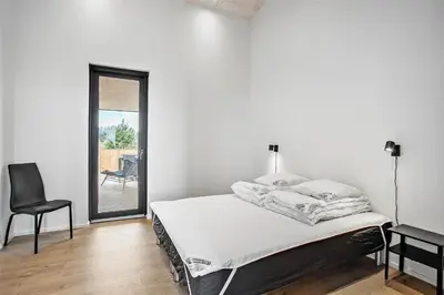 a white bedroom with a bed and a chair at JB141-Brovst-Kronvildtvej-86 in Brovst