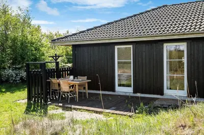 a black cottage with a table and chairs on a deck at JB908-Brovst-Kronvildtvej-190 in Brovst