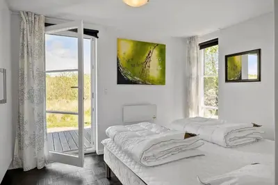 a white bedroom with two beds and a window at JB908-Brovst-Kronvildtvej-190 in Brovst