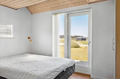 a bedroom with a bed and a sliding glass door at JB169-Brovst-Kronvildtvej-126 in Brovst