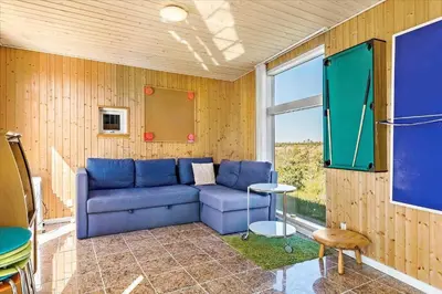 a living room with a blue couch and a window at JB169-Brovst-Kronvildtvej-126 in Brovst