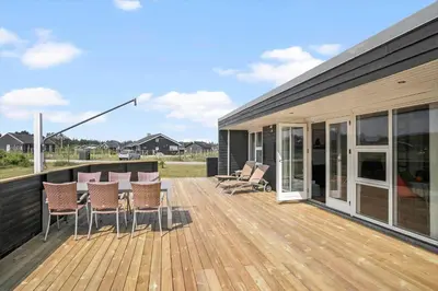 a deck with chairs and tables on a house at JB169-Brovst-Kronvildtvej-126 in Brovst