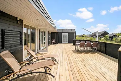 a wooden deck with chairs and tables on a house at JB169-Brovst-Kronvildtvej-126 in Brovst
