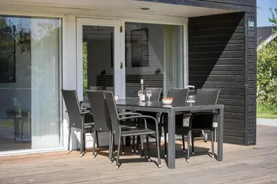a black dining table and chairs on a deck at JB221-Brovst-Kronvildtvej-182 in Brovst