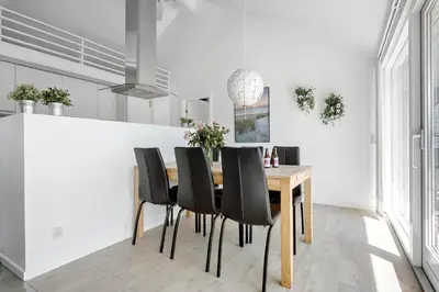 a dining room with a wooden table and black chairs at JB221-Brovst-Kronvildtvej-182 in Brovst