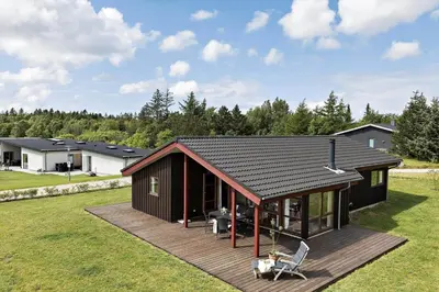 a small house with a wooden deck in a yard at JB188-Fjerritslev-Kollerup-Klitvej-163 in Fjerritslev