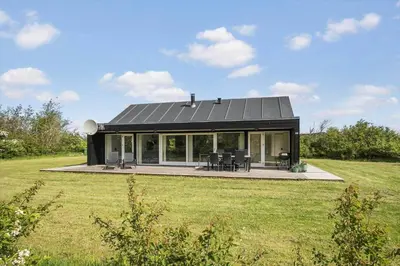 a house with a black roof on a field at JB752-Brovst-Kronvildtvej-210 in Brovst