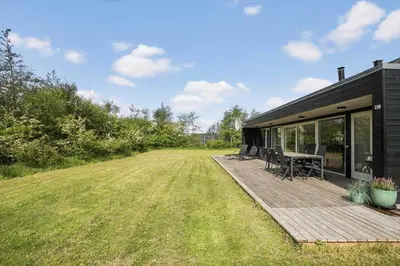 a house with a deck with a table and chairs at JB752-Brovst-Kronvildtvej-210 in Brovst