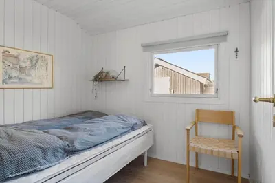 a bedroom with a bed and a chair and a window at JB195-Fjerritslev-Bogevej-36 in Fjerritslev