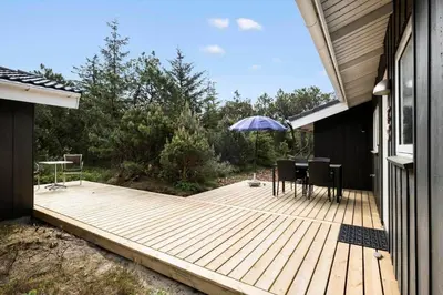 a wooden deck with a table and an umbrella at JB260-Fjerritslev-Blabaerstien-76 in Fjerritslev