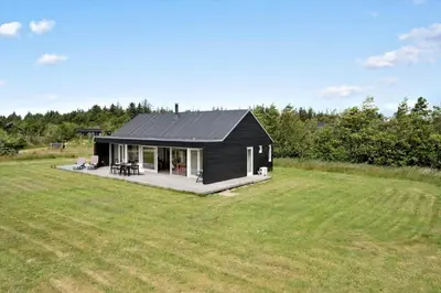 a black house in a field with a large yard at JB359-Brovst-Kronvildtvej-242 in Brovst