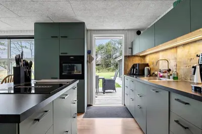 a kitchen with green cabinets and a door to a patio at LK2185-Lokken-Marthinesvej-17 in Løkken