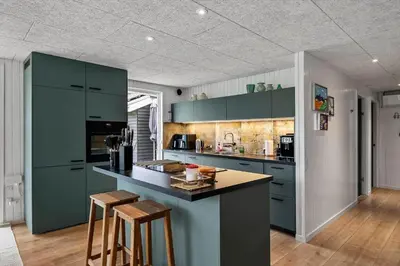 a kitchen with green cabinets and a counter with stools at LK2185-Lokken-Marthinesvej-17 in Løkken