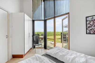 a bedroom with a bed and a large glass window at 70721-Ulfborg-Klitengene-11 in Ulfborg