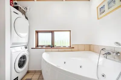 a white tub in a bathroom with a washing machine at 70721-Ulfborg-Klitengene-11 in Ulfborg