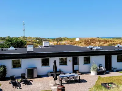 a white house with a picnic table and chairs at Family-Friendly House with Sauna in Pandrup