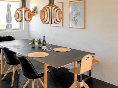 a dining room with a table with chairs and two lights at Family-Friendly House with Sauna in Pandrup