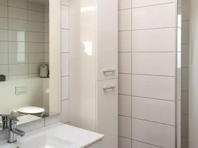 a white bathroom with a sink and a shower at Family-Friendly House with Sauna in Pandrup