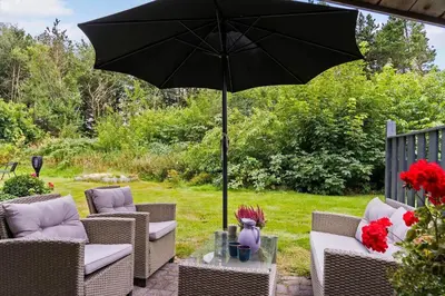 an umbrella on a patio with chairs and a table at JB162-Fjerritslev-Ronnevej-4 in Fjerritslev