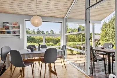 a dining room with a table and chairs and windows at JB403-Fjerritslev-Poppelvej-20 in Fjerritslev
